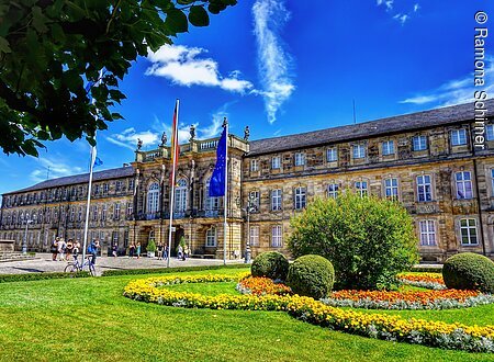 Ein prachtvolles Schloss, davor eine grüne Gartenanlage.