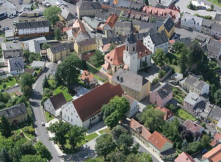 Stadtansicht (Arzberg, Fichtelgebirge) Luftaufnahme einer kleinen Stadt mit Kirche, Wohnhäusern und Straßen, umgeben von Bäumen.