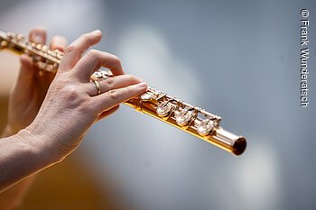 Zwei schlanke Hände halten eine Querflöte